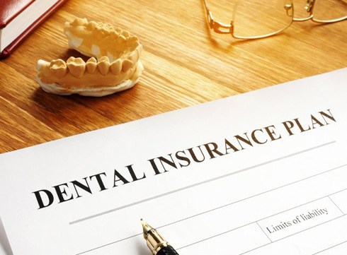 a dental insurance form next to a denture model