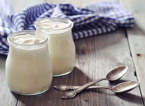 Two jars of yogurt with spoons on wooden table