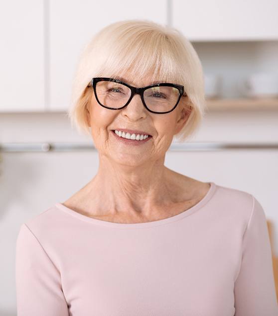 Senior woman with glasses smiling in a kitchen