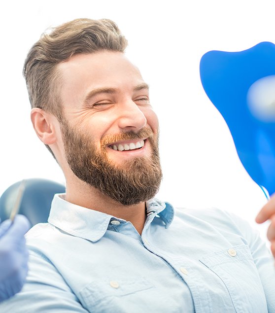 patient smiling while looking in dental mirror