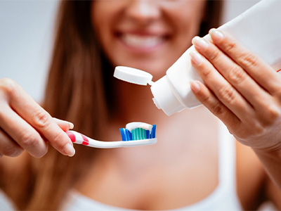 Smiling woman putting toothpaste onto a toothbrush