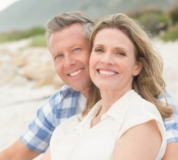 Man and woman with dental implant supported replacement teeth smiling