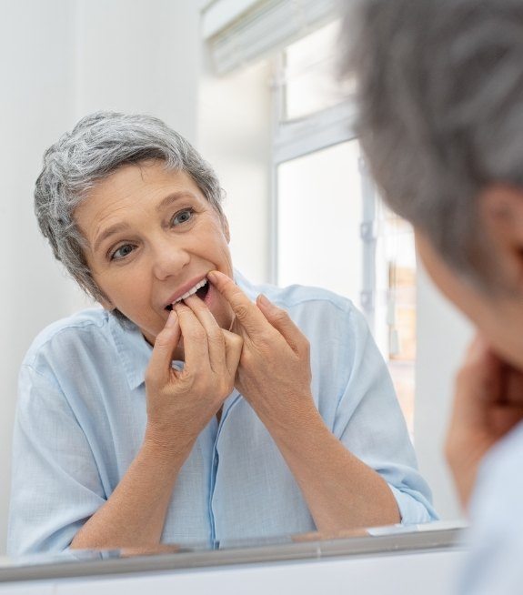 Woman flossing teeth before periodontal cleaning