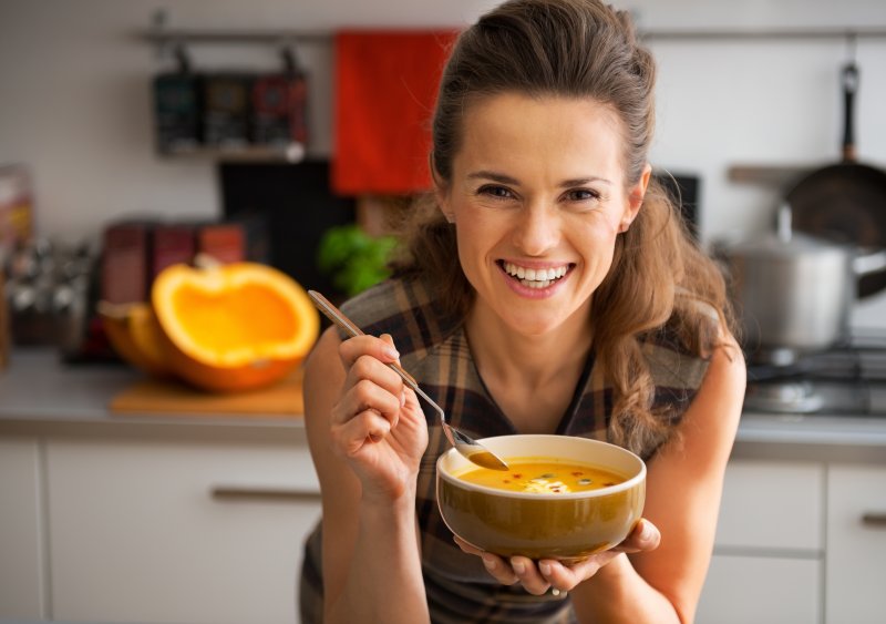 a woman smiling while holding a bowl of soup